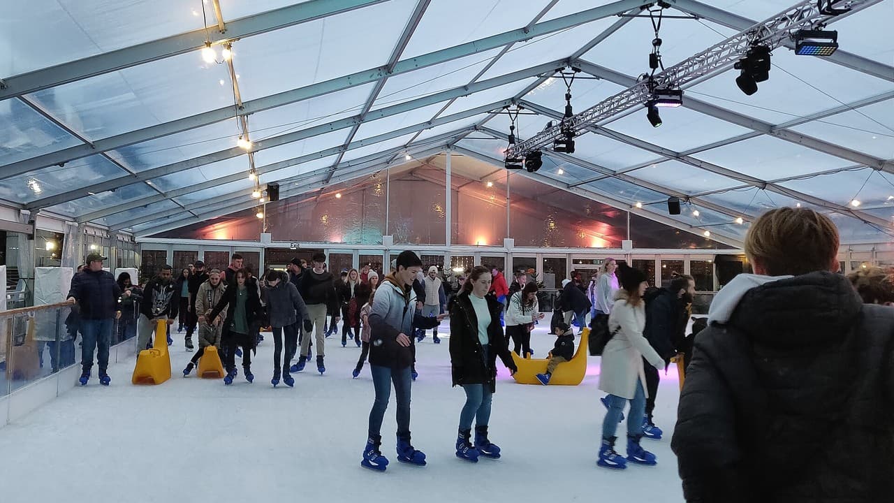 Skaters on the ice inside the covered Portsmouth On Ice rink in Guildhall Square
