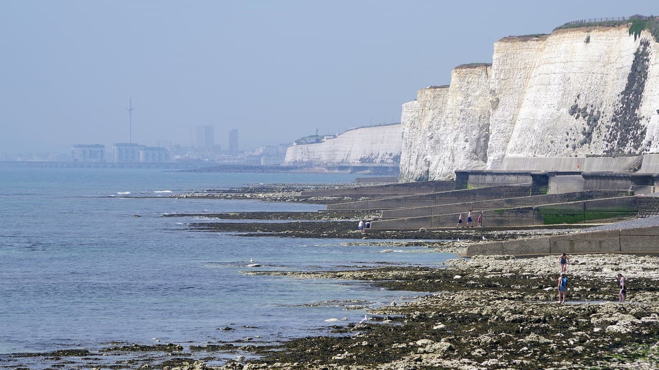 White chalk cliffs at Peacehaven with the sea on the left and the Brighton skyline and the i360 in the distance