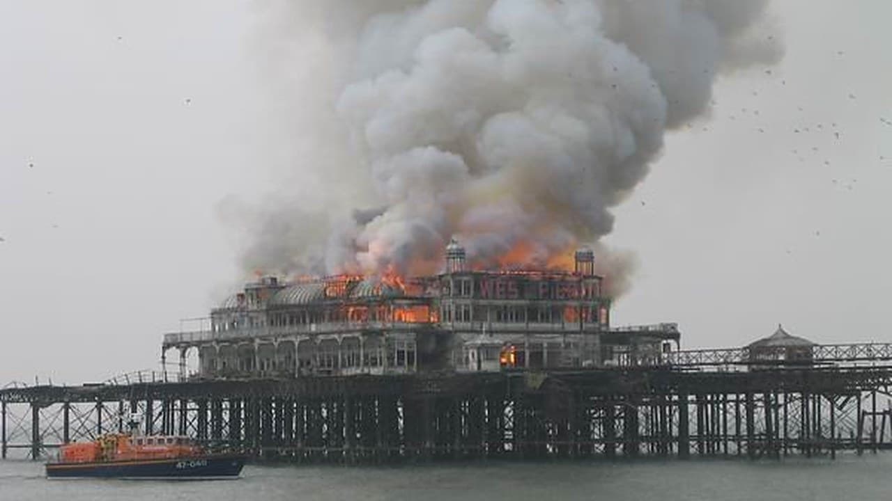 The West Pier on fire in March 2003, with smoke rising over the burning building and an orange lifeboat in the foreground